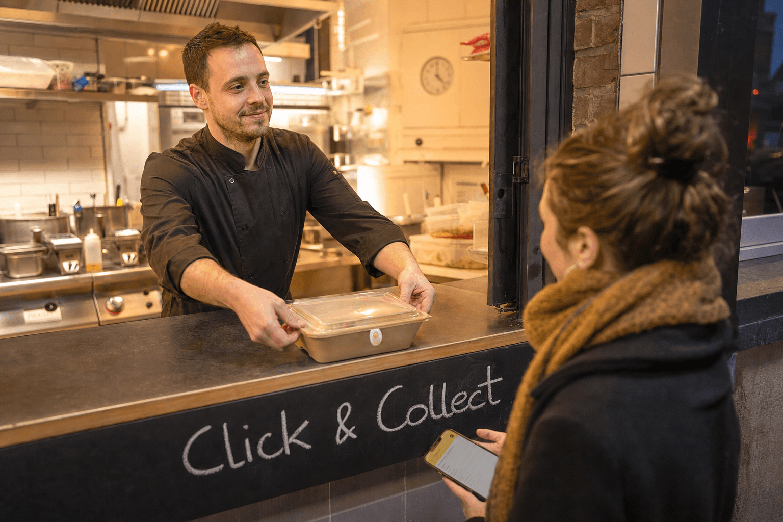 Chef de restaurant à Mons emballant un plat à emporter étiqueté Click & Collect, client attendant à la porte